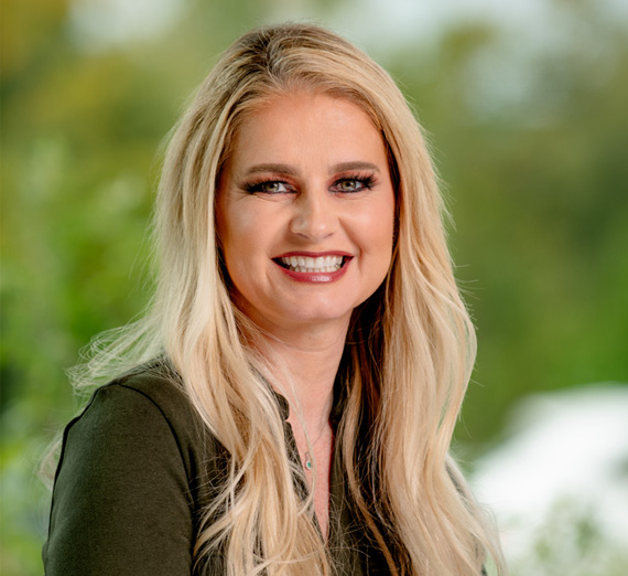 A group of five people stand together in a brightly lit hospital hallway, smiling at the camera. Two wear stethoscopes and medical attire, one wears a Gonzaga University sweatshirt, and others are dressed in casual or professional clothing, representing a mix of students and healthcare professionals.
